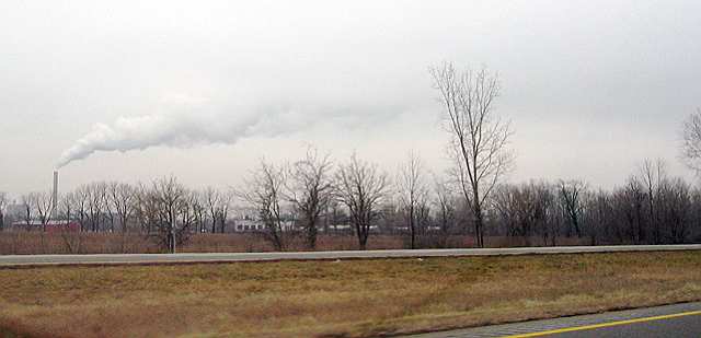 An industrial plant sends a steady stream of steam or smoke into the winter air, somewhere in Ohio.