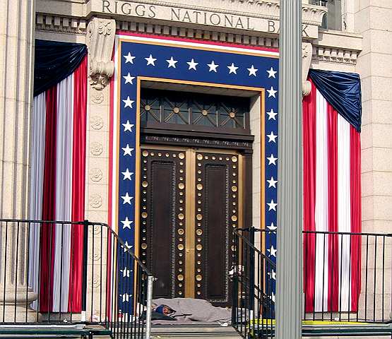 A pair of homeless men sleep beneath some stars and stripes on Pennsylvania Avenue half a block from the White House.