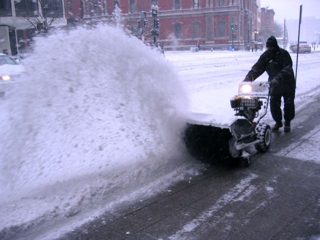 A worker blows snow from the sidewalk along Pennsylvania Avenue yesterday after D.C. got about three inches of snow.