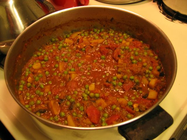 A pot of freshly-made aloo mutter bubbles on the stove.