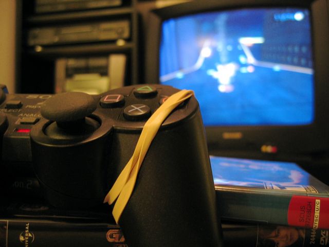 A rubberband holds down the action button on this PS2 controller so that someone can collect as many bolts as possible in Ratchet and Clank.