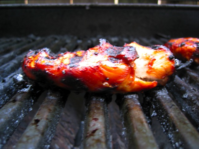 A chicken breast sizzles on the grill.