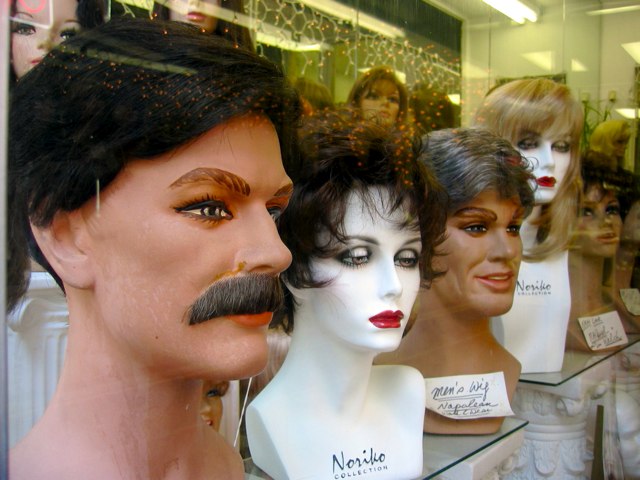 A display of wigs for men in the same storefront.