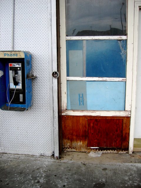 A battered door beside an equallly battered payphone in NE D.C.