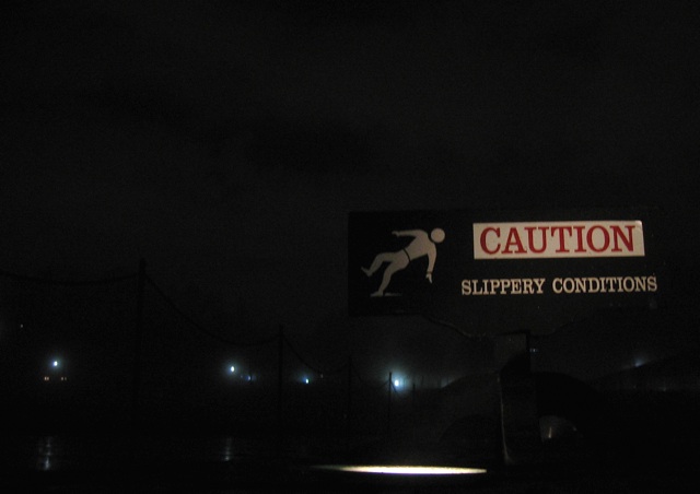 A tiny little caution sign sits alongside the Vietnam Veterans Memorial on a wet and foggy morning.