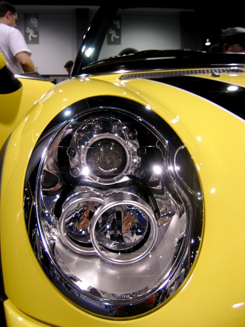 The headlight on a shiny new Mini Cooper convertible.