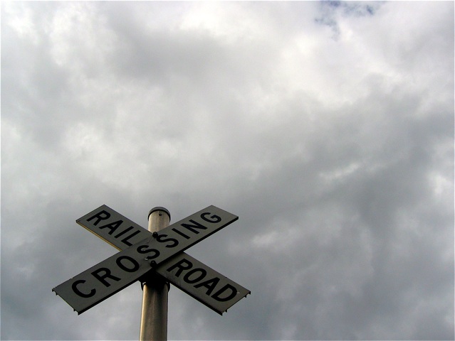 A railroad crossing sign east of Missoula beneath a cloudy summer sky.